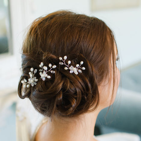 Woman with low side bun sat down with pearl hairpins set in to the bun