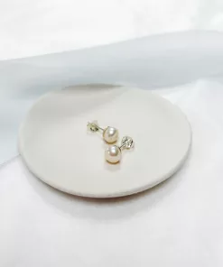 Freshwater pearl stud earrings in silver set on a small ivory dish with blue ribbon