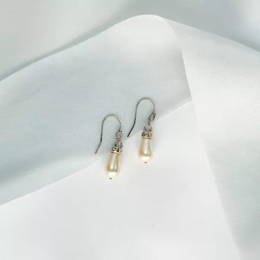 Pearl and crystal drop earrings in gold on an ivory fabric background with blue ribbon