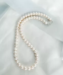 Traditional string of pearls bridal necklace set on a fabric background with blue ribbon