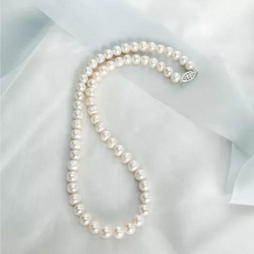 Traditional string of pearls bridal necklace set on a fabric background with blue ribbon