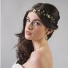 Woman with long dark wavy hair looking at the camera with a Delicate boho bridal hair vine in her hair. The background is grey.