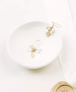 crystal freshwater pearl leaf drop cluster earrings set on a small dish with plain background and ivory silk ribbon