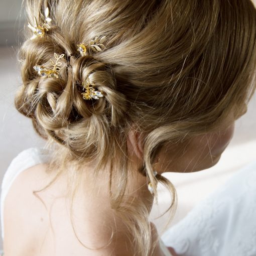 Dawn Chorus Hair pins. Bride with blonde hair in a messy bun with floral and leaf hairpins scattered through.