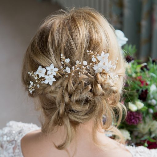 Back of Ladies head with blonde hair with a messy bun and bridal gown, showing 2 floral hair pins nestled into the bun. Clematis Wedding Hairpin