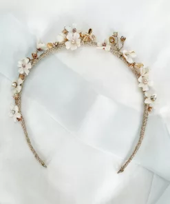 Dancing bee tiara. Tiara with blush crystals and pearls, ivory pearls and handmade flowers set on a gold band laid out on an ivory fabric background with blue ribbon