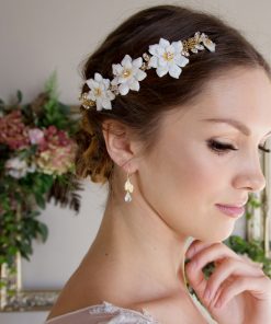 Bride stood in front of an antique gold picture frame decorated with hydrangeas and greenery. She wears a decorative flower headdress and gold leaf earrings.