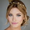 woman with blonde hair looking directly at the camera, with her hair in a low messy bun, wearing a celestial bridal halo hair vine