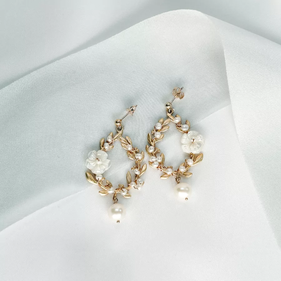 floral pearl romantic chandelier bridal earrings set on top of a blue silk ribbon draped over an ivory fabric background