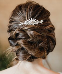 Shoulders and back of the head view of a bride. She stands in front of a stone wall. Her hair is dark and she has a curly bridal hair bun with Statement crystal wedding hair comb in.
