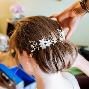 Bride is having floral hair pins inserted into her bridal bun just before the ceremony