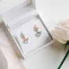 Gold diamante art deco style earrings in a jewellery box with blush silk ribbon in the background and a white rose.