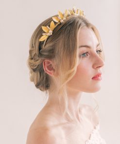 Woman with blond hair styled up on a low braid wearing an off the shoulder lace dress with large gold leaved wedding crown