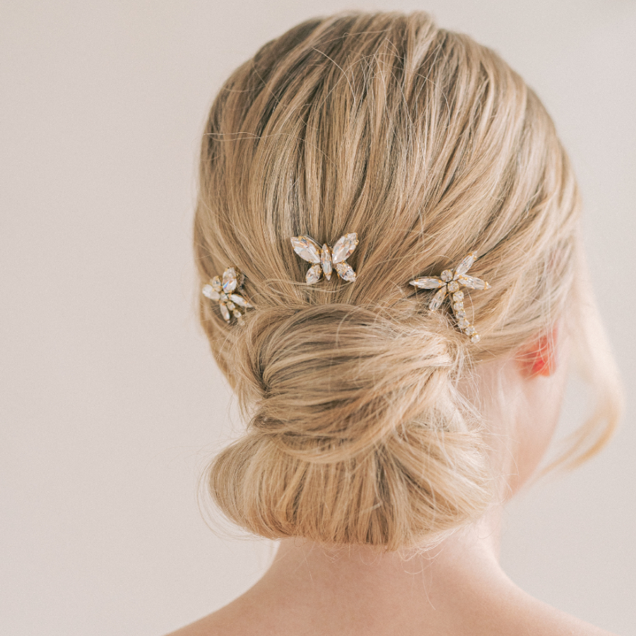 Image shows back of brides head, with blonde hair up in a braided bun, with Damselflies and Butterfly crystal bridal hair pins