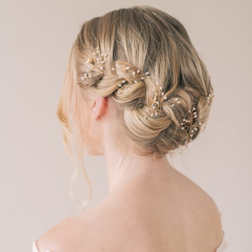 Image shows a bridal hair braid with hair up and small hairpins with pearls decorating the braid.