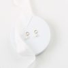 Contemporary circle stud pearl drop earrings on small white round platform with ivory silk ribbon and ivory fabric background