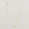 delicate classic freshwater pearl bridal pendant in gold sat on a beige background.