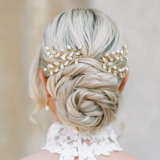 Bride with blonde hair in low spiral bun with two diamante crystal bridal hair pins. She is looking away from the camera, and has a choker style neckline to the dress with lace.