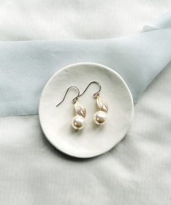 Image of Pearl Drop wedding Earrings on small ivory dish, on a cream fabric background with blue ribbon