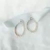 Image shows white fabric background with blue silk ribbon and large hoop bridal stud earrings with pearls in gold.