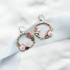 flower hoop bridal earrings laying flat on ivory material with blue ribbon