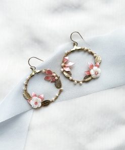 gold hoop earrings with leaves and flowers laying flat on ivory material with blue ribbon