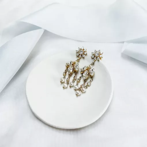 Marguerite crystal Pearl Earrings.Image shows white fabric background with blue silk ribbon draped across, with small clay bowl on top with crystal and pearl drop earrings.