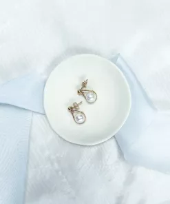 Vivienne Pearl Drop Earrings - image shows white background with blue silk ribbon draped across and a small ivory clay bowl with gold stud pearl drop earrings