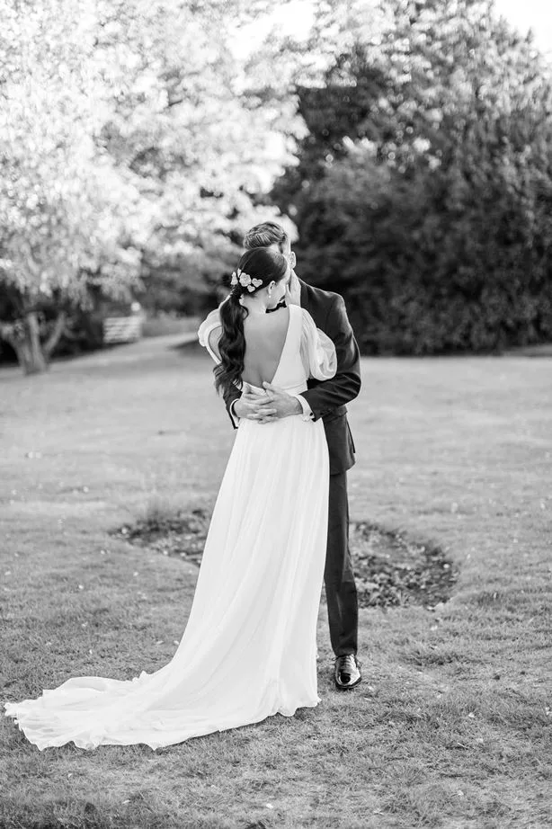 Couple embracing in a garden in a wedding gown and mens wedding suit