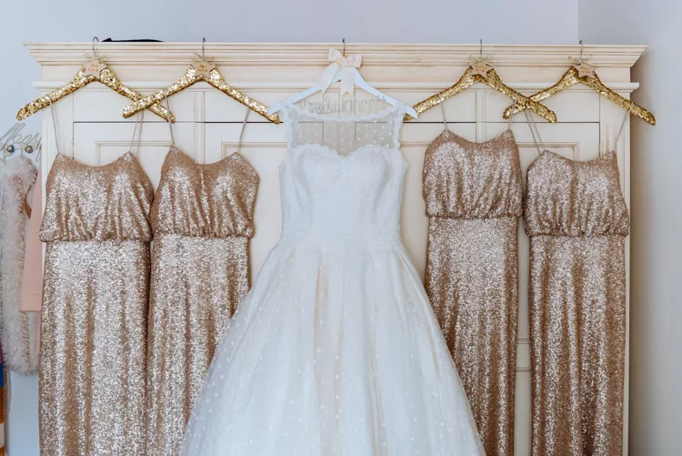 Is it normal to feel anxious planning a wedding? Wedding gown and 4 gold sparkly bridesmaid dresses all hanging up on a wardrobe