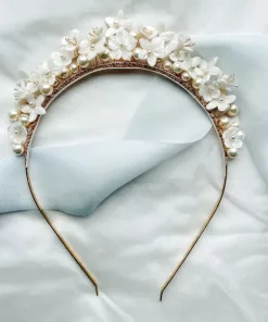 Flower pearl bridal crown laying on a cream material background with blue silk ribbon