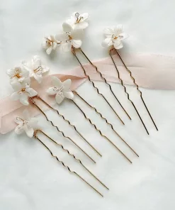 delicate wedding flower hair pins for buns lying flat on ivory fabric with blush pink ribbon