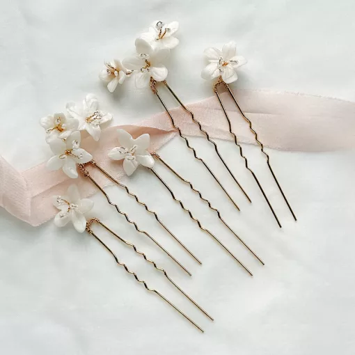 delicate wedding flower hair pins for buns lying flat on ivory fabric with blush pink ribbon