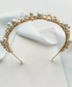 large pearl wedding headband propped up with a white flat background with little blue silk ribbon.