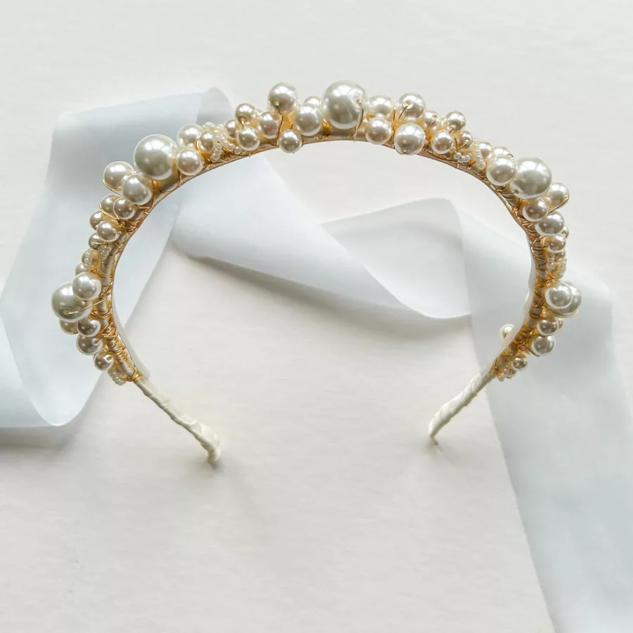 large pearl wedding headband propped up with a white flat background with little blue silk ribbon.