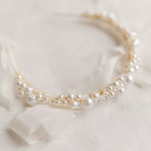 large pearl wedding headband laying on an ivory flat background