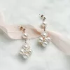 luxury large real pearl drop earrings with gold studs laying on an ivory fabric background with blush pink ribbon