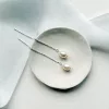 threader chain Long pearl bridal earrings set on a small cream dish. It sits on a while background with light blue silk ribbon.