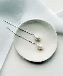threader chain Long pearl bridal earrings set on a small cream dish. It sits on a while background with light blue silk ribbon.