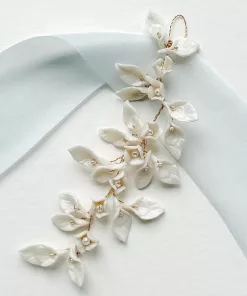Bridal updo wedding hair vine with clay leaves and pearls resting on a plain white background with light blue silk ribbon.