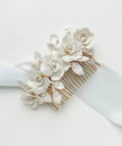 Wedding hair comb with rose flowers and pearls set on a gold wire comb and laying on a white background with soft blue silk ribbon