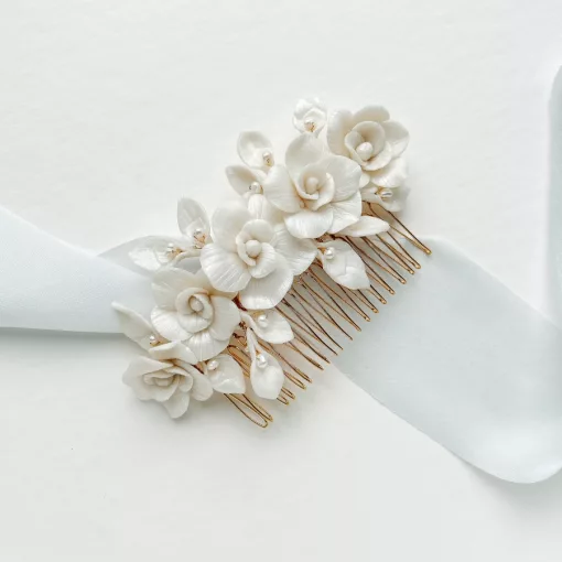 Wedding hair comb with rose flowers and pearls set on a gold wire comb and laying on a white background with soft blue silk ribbon